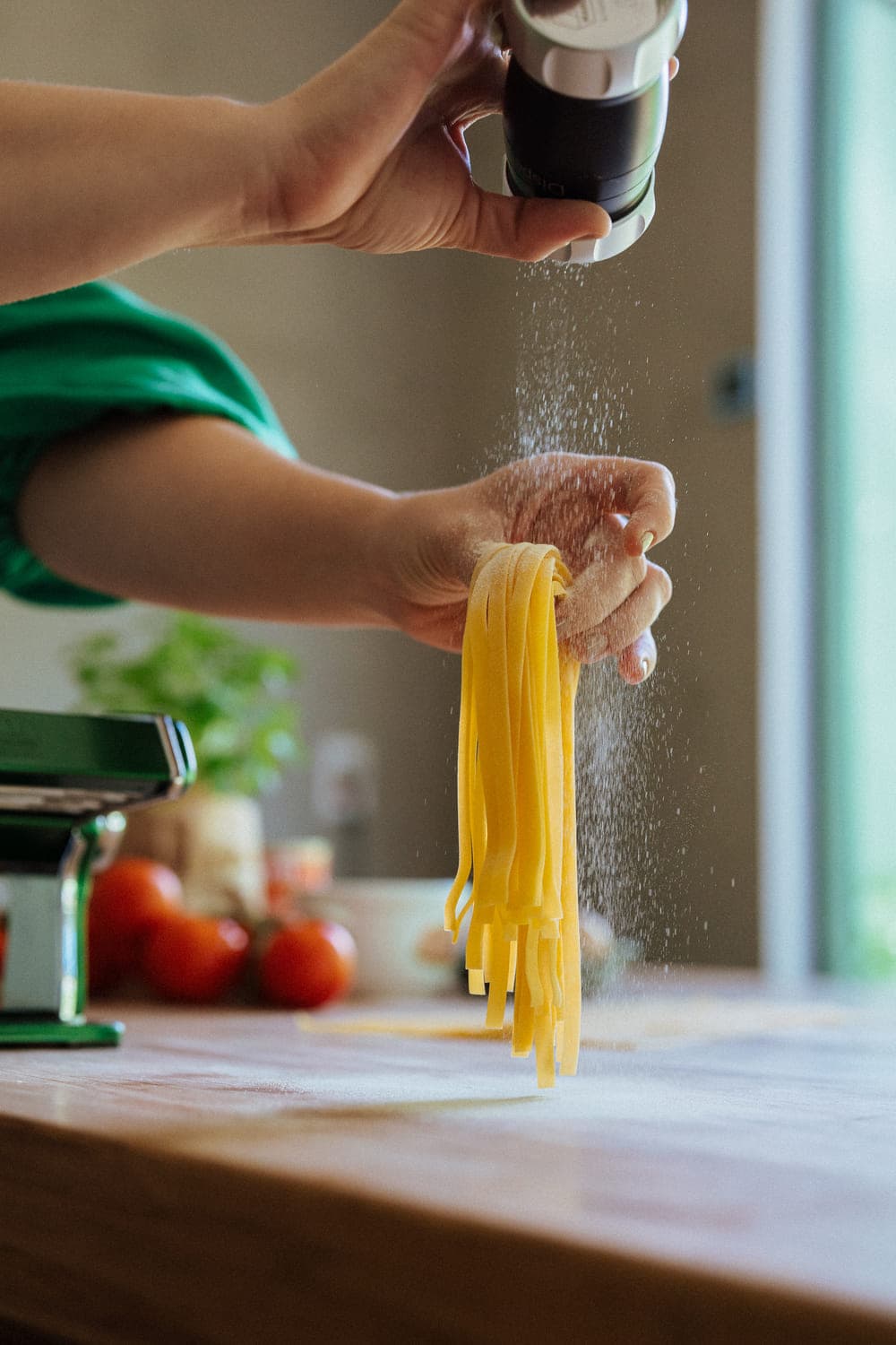 Mãos sovando massa fresca all'uovo em superfície de mármore